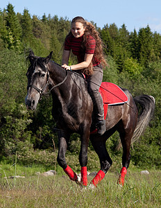 一个女孩骑着马在飞快地骑着一匹马场景鬃毛头发森林运动边缘青少年马背动物黑发图片