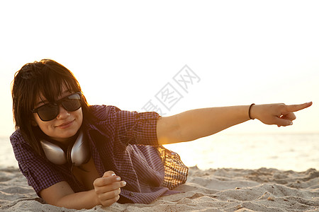 美丽的黑发女孩 在沙滩沙滩上戴耳机音乐太阳镜拥抱日出自由幸福头发海滩说谎假期图片