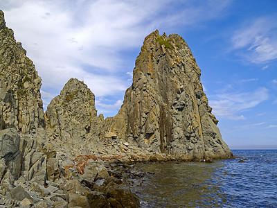 水石头海岸上的岩石蓝色海湾天空石头海浪灰色背景