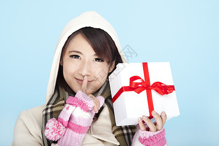 一个带着礼物盒微笑的女人的冬季肖像图片