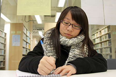 亚裔女性在大学深造考试测试微笑笔记本图书馆知识收藏书架课堂生活图片