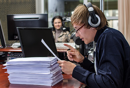在收音机麦克风前的有趣的主播工人职员男人播送耳机主持人女孩娱乐工作乐趣图片