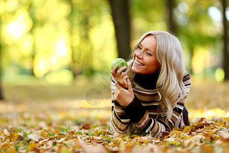 拥有绿苹果的妇女微笑成人木头女性季节乐趣金发女郎食物森林青少年图片