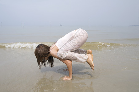 在海滩上做瑜伽的亚洲女孩日出岩石运动身体海洋保健冥想日落卫生专注图片