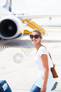 离开机场的年轻女子 即将登上飞机运输跑道翅膀微笑旅行女孩女士女性快乐乘客图片