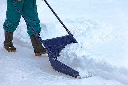 暴风雪发生后手工除雪 并用积雪铲雪车道雪堆降雪院子员工工作季节工具蓝色风暴图片