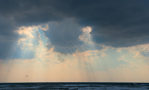 黑暗的暴风雨背后的太阳笼罩着大海图片
