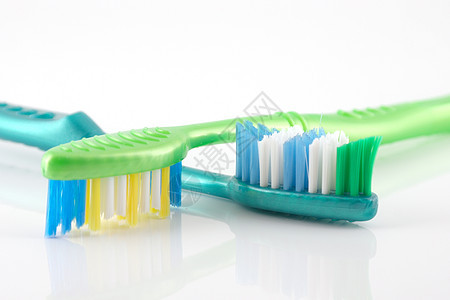 两个牙刷绿色黄色塑料假牙反射美丽宏观牙医白色漱口水图片