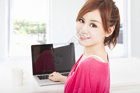 带着笔记本电脑坐着微笑的年轻女子图片