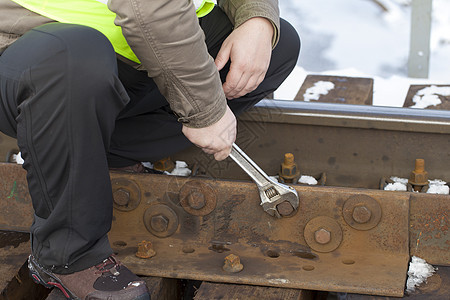 铁路工人在铁路桥上用扳手修理坚果图片