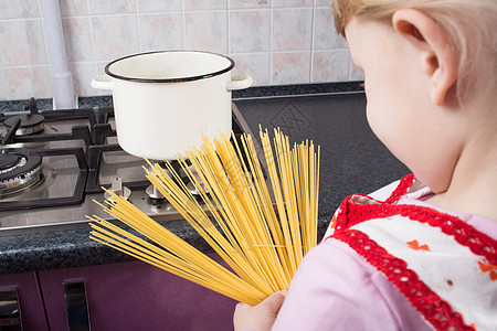 女孩看着意大利面帮助推杆女性食物童年女儿紫色孩子烹饪炊具图片