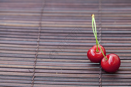 背景墙面竹垫上两颗樱桃放在盘子里工作室宏观材料木头叶子食物水果生活竹子活力背景