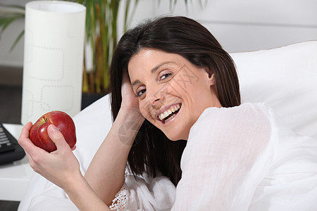 手拿着苹果的睡在床上的女人图片