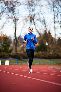 年轻妇女在赛场和田径体育场跑步女孩娱乐女性快乐运动员运动竞技竞赛活动蓝色图片