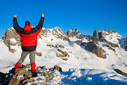 在冬山中徒步旅行边缘自由悬崖石头优胜者风险喜悦活力手臂蓝色图片