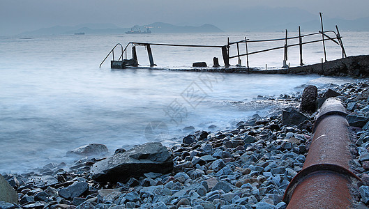 旧金属管道和通往海洋的道路运动卵石反射旅行场景力量脚步石头岩石海滩图片