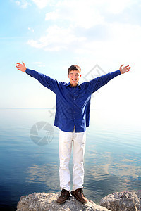 幸福快乐的青少年微笑天空岩石青年享受蓝色阳光衬衫男人乐趣图片