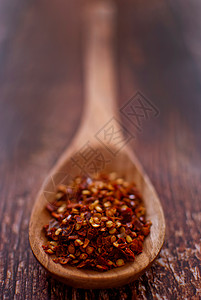 咖喱香料红辣椒薄片红色寒冷草药厨房木头地面食物树叶勺子美食背景