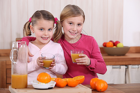 两个姐妹在厨房里喝橙子汁图片
