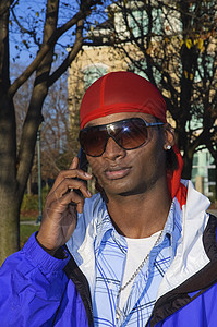 使用手机的非裔年轻美国人男子男人耳环细胞电话男性太阳镜微笑多样性背景图片