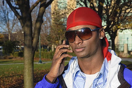使用手机的非裔年轻美国人男子电话多样性男人太阳镜男性微笑细胞耳环背景图片