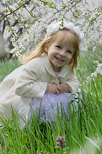 微笑的女孩坐在春花花园的春花园里图片
