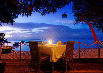 日落时吃晚饭日出蓝色玻璃蜡烛餐厅食物海洋桌布奢华支撑图片