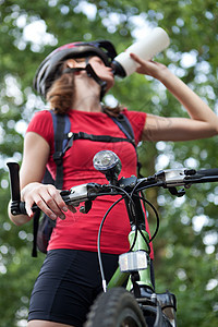 漂亮的年轻女子骑摩托车 在她山上骑着自行车成人森林喜悦头盔运动活动女孩天空女性娱乐图片