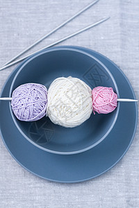 盘子上闪亮的毛线和编织针头球紫色站立灰色白色喜悦针织粉色水平桌布闲暇图片