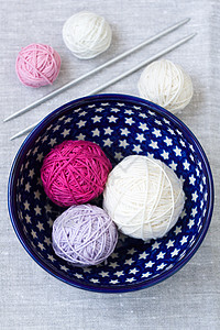 盘子上闪亮的毛线和编织针头球蓝色线圈粉色站立星星消遣灰色桌布白色针织图片