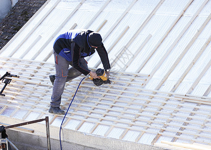 屋顶在木柴新屋顶上工作工具天空建设者锤子男性劳动木匠建设指甲工人图片