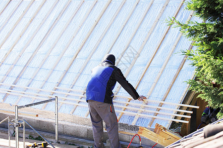 屋顶在木柴新屋顶上工作瓦工男性工匠房子天空工具锤子劳动者工艺住房图片