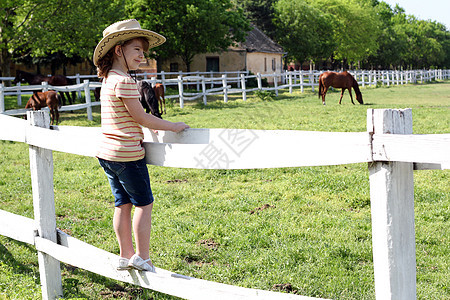 戴着牛仔帽的小女孩 站立在畜栏和看球衣上图片