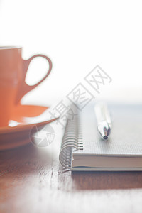 橙色咖啡杯 笔和木制桌上的笔图片