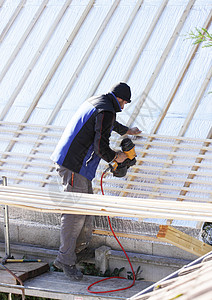 屋顶在木柴新屋顶上工作劳动构造天空建设者建设房子工具瓦工维修卵石图片