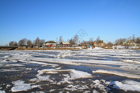 在靠近村庄的河流上驱冰房子城市天气蓝色太阳风景天空石头场景季节图片
