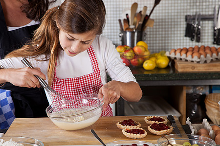 母亲和女儿在家烘烤厨师乐趣女孩面糊闲暇食物帮助甜点学习活动图片