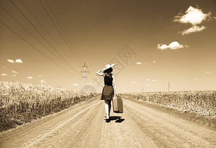 在乡村公路上带着手提箱的孤独女孩裙子国家衣服小路场地村庄女孩农村女性自由图片