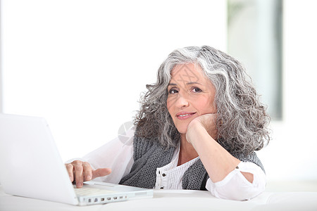 灰色电脑带笔记本电脑的成年灰色头发女士背景