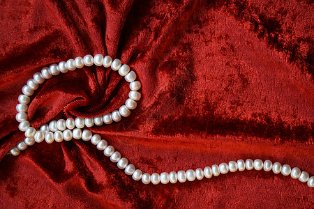 红丝绸白珍珠项链在天鹅绒上宝石珍珠珠子礼物丝绸光泽度细绳魅力手镯展示背景