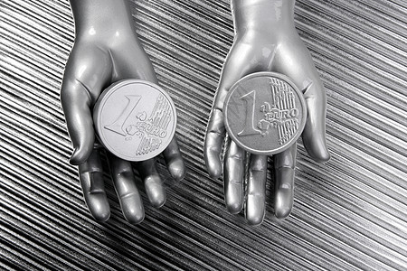 未来机器人手中的两枚银欧元硬币手指订金储蓄金融投资收益宝藏货币金属现金图片