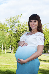 怀孕的年轻女孕妇微笑婴儿裙子成人黑发紫色公园腹部父母母亲女性图片
