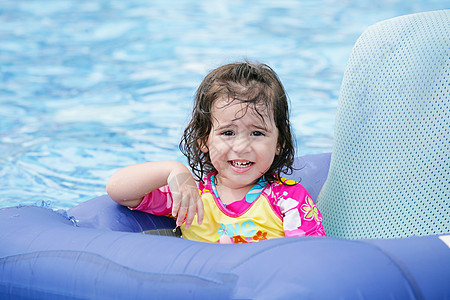 宝宝女孩玩得开心 在蓝色的漂浮到热带游泳池图片