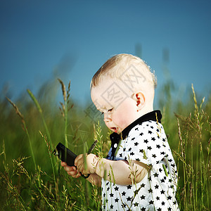 男孩在草地上打来电话场地蓝色孩子讲话天空木头男性头发喜悦儿子图片