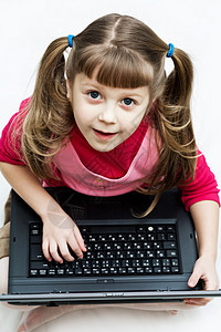 带笔记本电脑的可爱女孩童年技术孩子教育闲暇文化商业学习幼儿园键盘图片