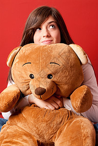 拥抱泰迪熊的年轻女人 看着坐在近身图片