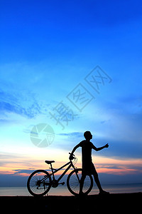 男人骑自行车的休眠钟 在附近美丽的湖边日落支撑闲暇成人天空海滩太阳数字车轮阳光图片