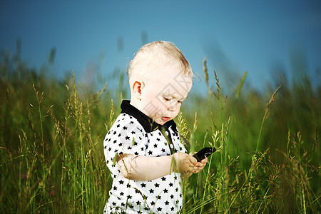 男孩在草地上打来电话喜悦木头讲话技术眼睛孩子场地儿子婴儿头发图片