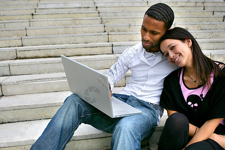 一对夫妇用笔记本电脑坐在一些台阶上图片