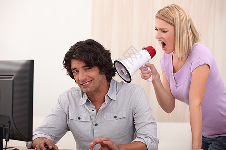 一个男人在做电脑 一个女人用扩音器对他大喊大叫图片